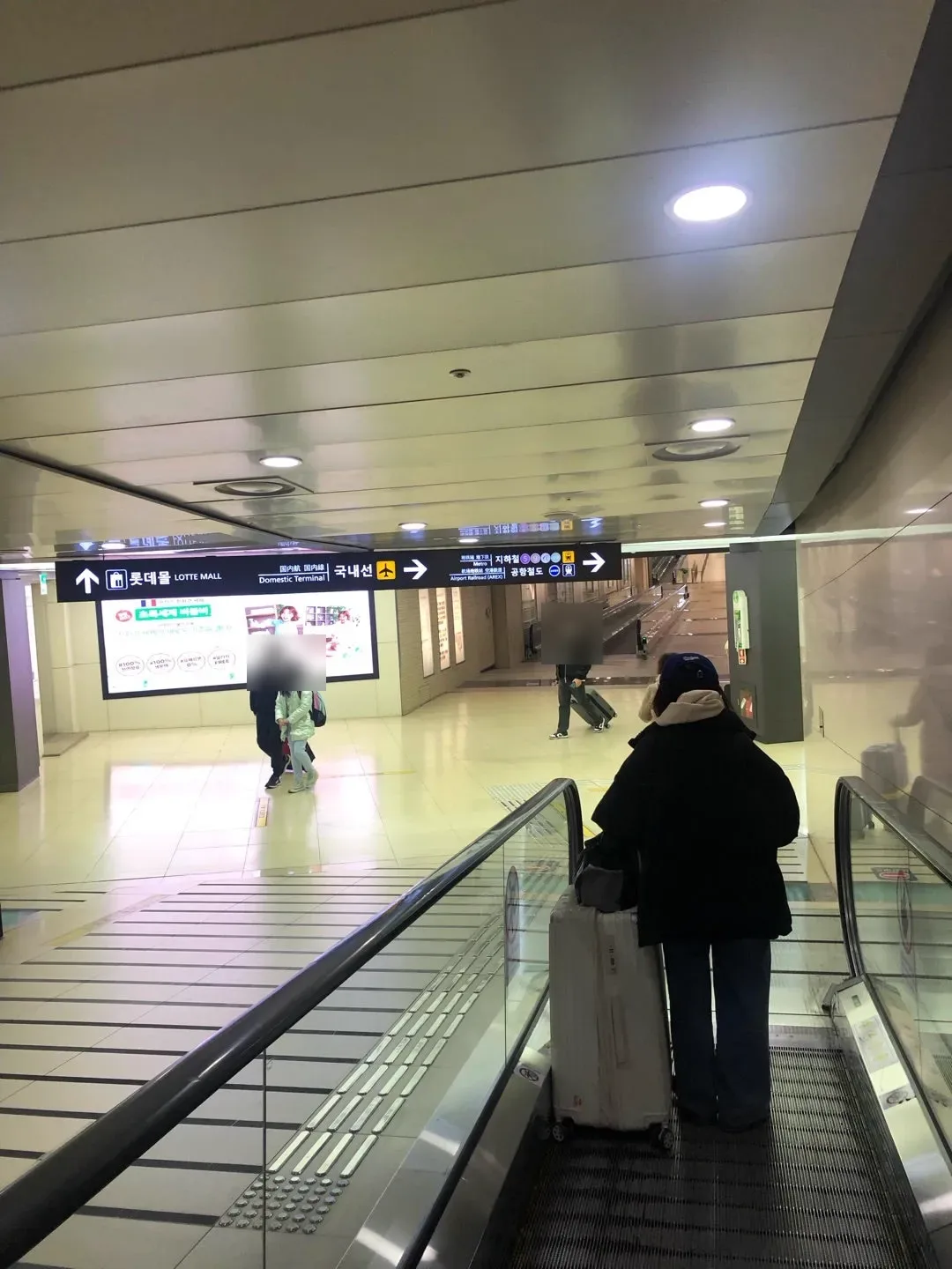 地下通路の動く歩道。天井の案内板に「롯데몰 LOTTE MALL」と「국내선（国内線）」の矢印が出ている