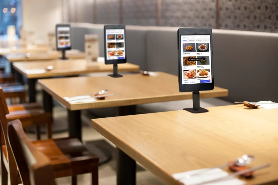 各テーブルに注文用のタブレットが置かれた飲食店