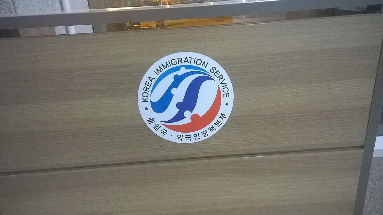 仁川空港の木目のカウンターに貼られた、「KOREA IMMIGRATION SERVICE 출입국·외국인정책본부」と書かれた丸いマーク