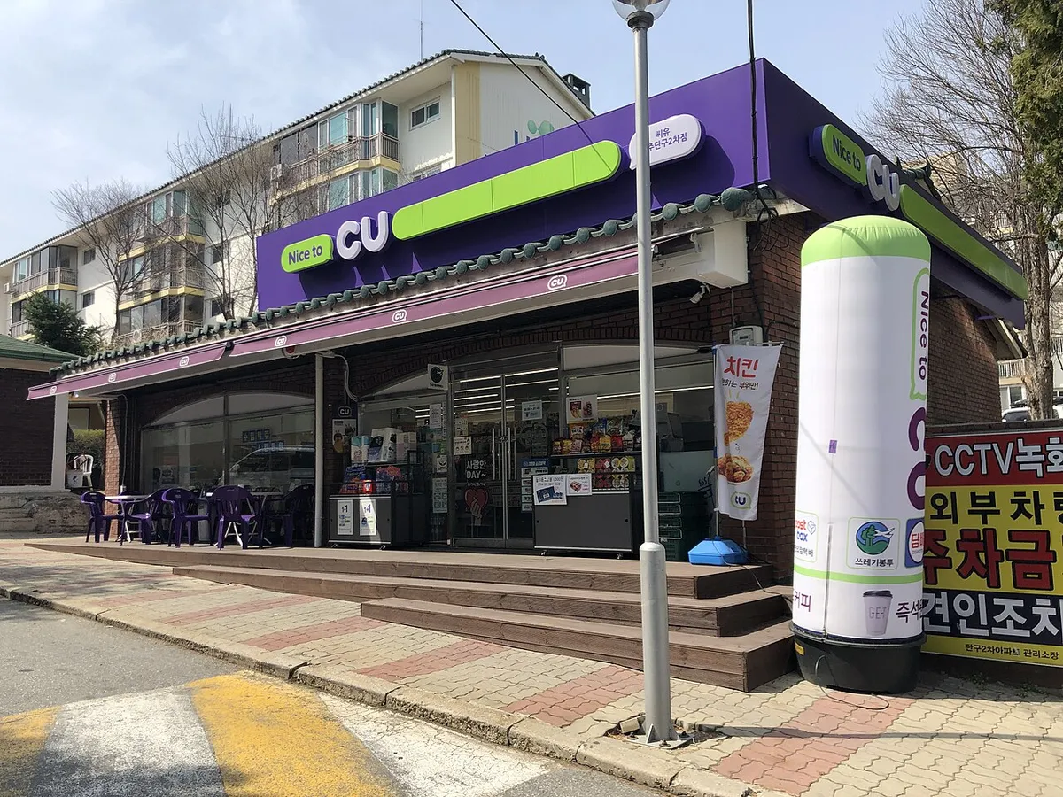 CUの店。紫と黄緑の看板で、店の前にテーブルといすがある