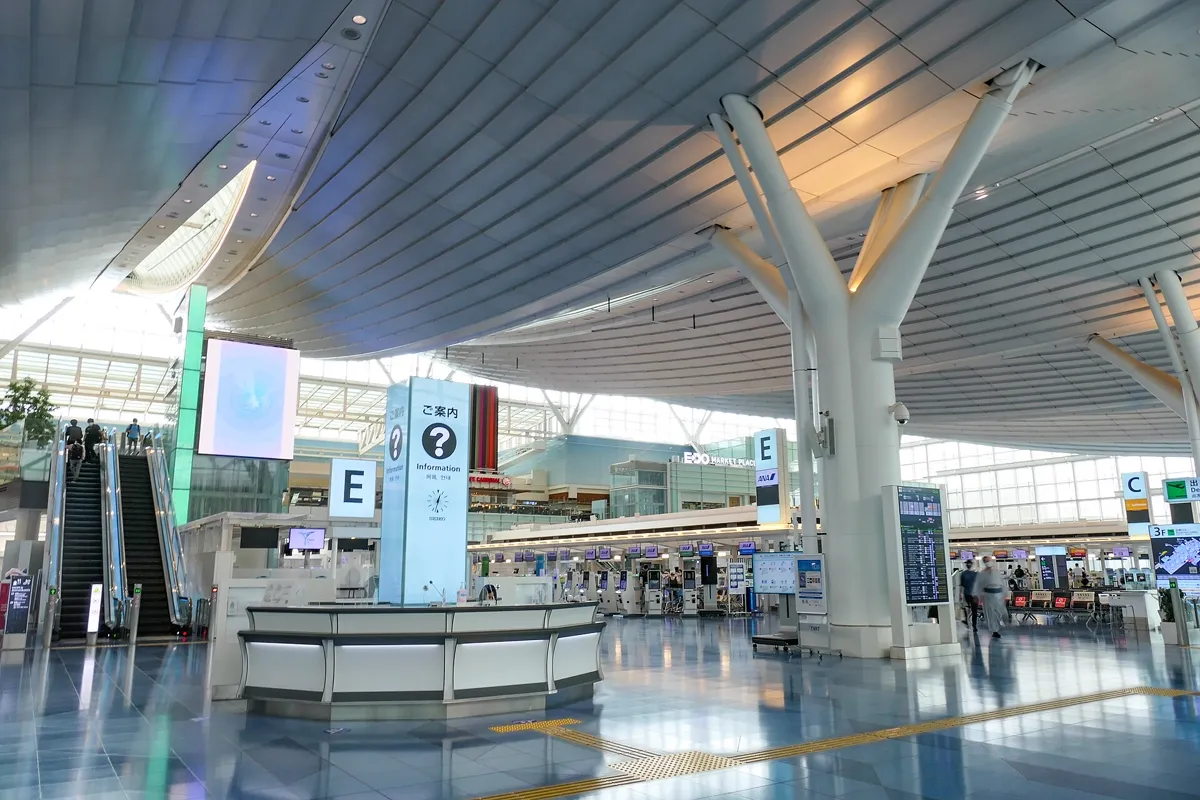 羽田空港第3ターミナルの出発ロビー。白い柱と高い天井の下にチェックインカウンターが並ぶ