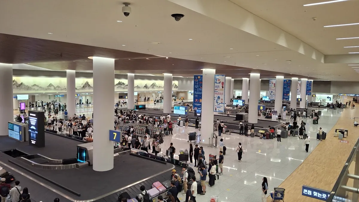 仁川空港第2ターミナルの荷物受取場。番号の付いたターンテーブルのまわりで、到着した人たちがスーツケースを待っている