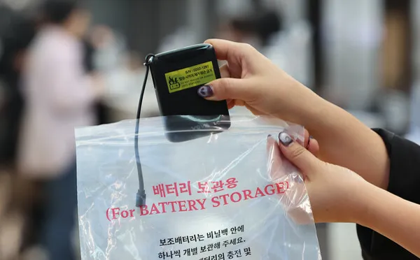 「배터리 보관용（For BATTERY STORAGE）」と書かれたビニール袋に、モバイルバッテリーを入れようとしている手元
