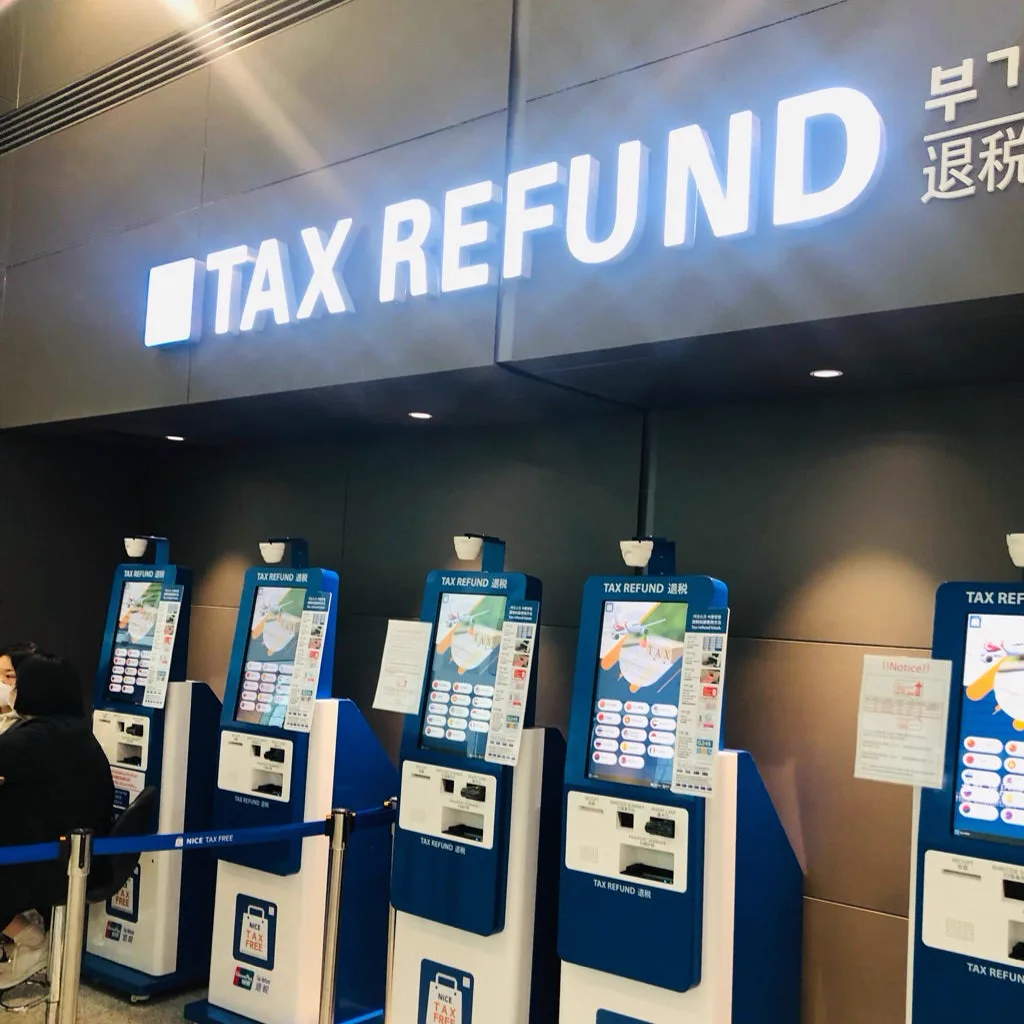 TAX REFUNDの看板の下に並ぶ青と白の還付キオスク