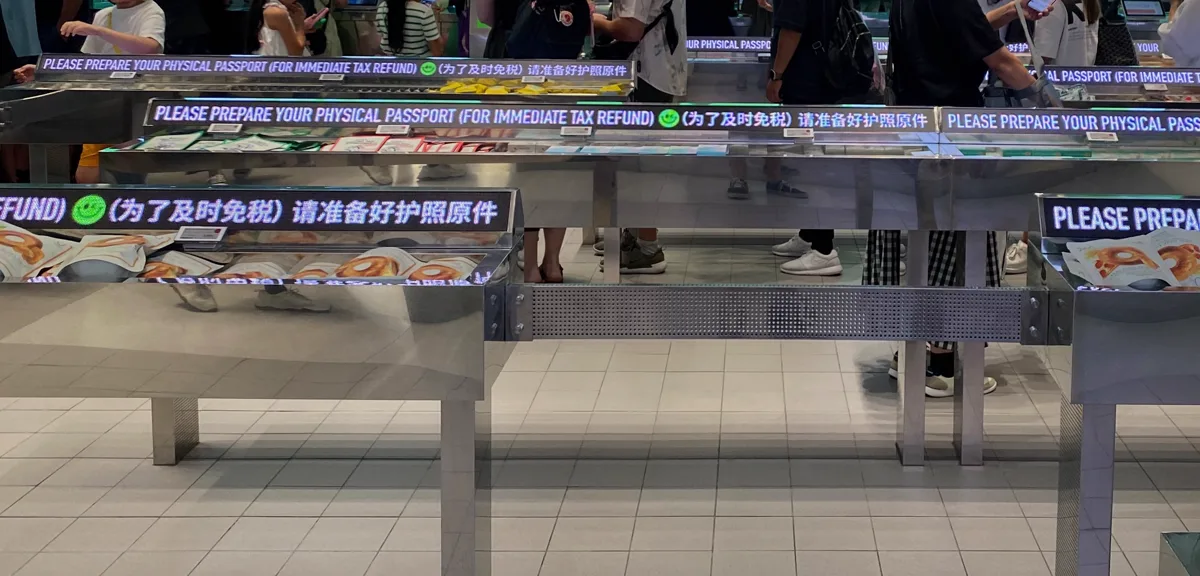 「PLEASE PREPARE YOUR PHYSICAL PASSPORT」と表示された会計カウンター