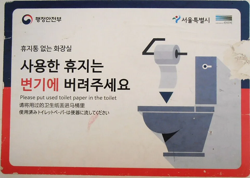 韓国の公衆トイレの張り紙。「사용한 휴지는 변기에 버려주세요（使ったトイレットペーパーは便器に流してください）」と韓国語・英語・中国語・日本語で書かれている
