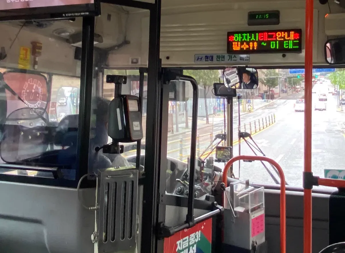 ソウルの市内バスの運転席のそば。交通カードの読み取り機があり、上の電光掲示に降りるときのタッチを呼びかける文字が出ている