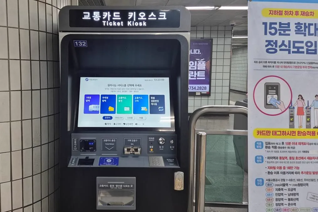 駅の券売機「교통카드 키오스크（Ticket Kiosk）」。画面では日本語を選べる。右は15分以内の再入場ルールを知らせるポスター