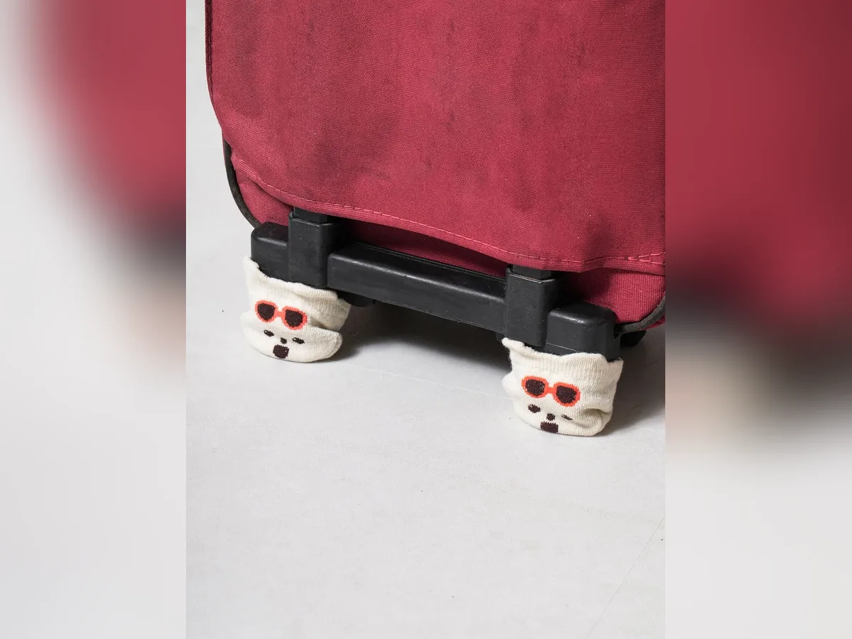 スーツケースの車輪にかぶせたクマの顔のカバー