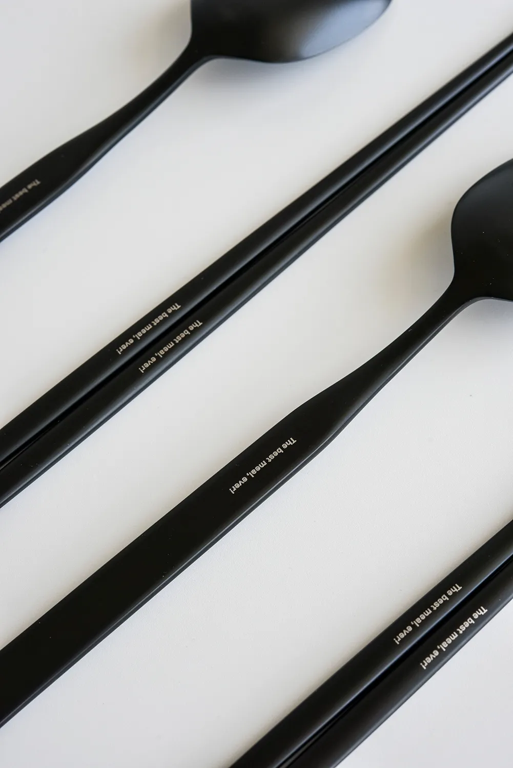 黒いスプーンと箸の柄に刻まれた、白い文字の名入れ