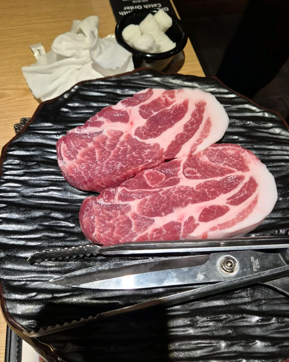 1PIG 益善店 — 黒い皿に盛られた厚切り豚肉