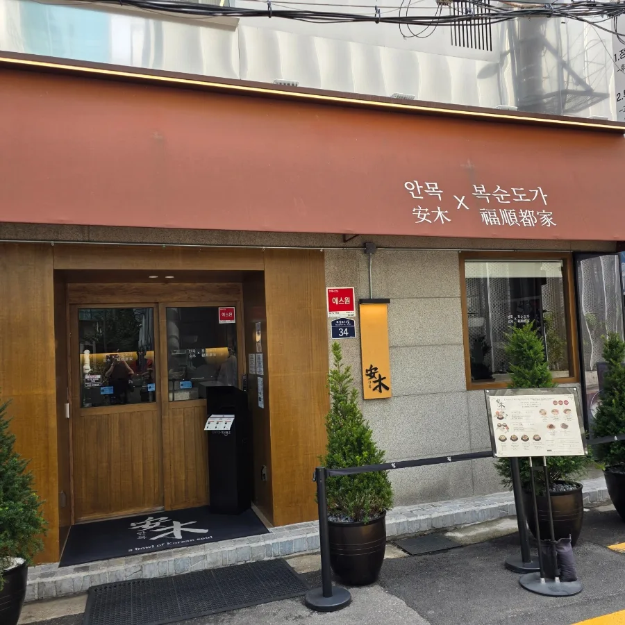 安木 聖水店 — オレンジ色の庇と木製の入口ドア
