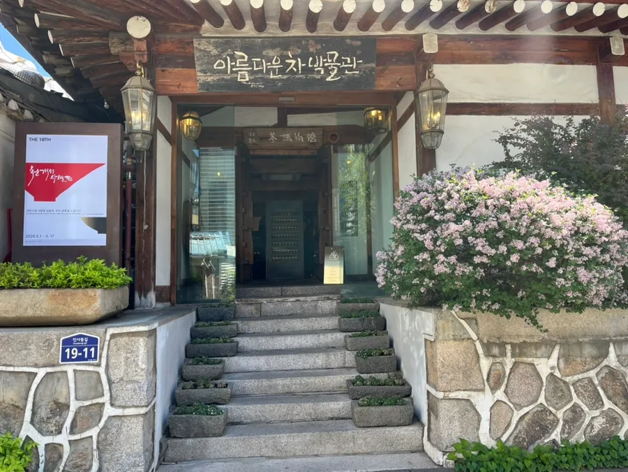 アルムダウン茶博物館 — 木の看板と花が迎える韓屋の入口