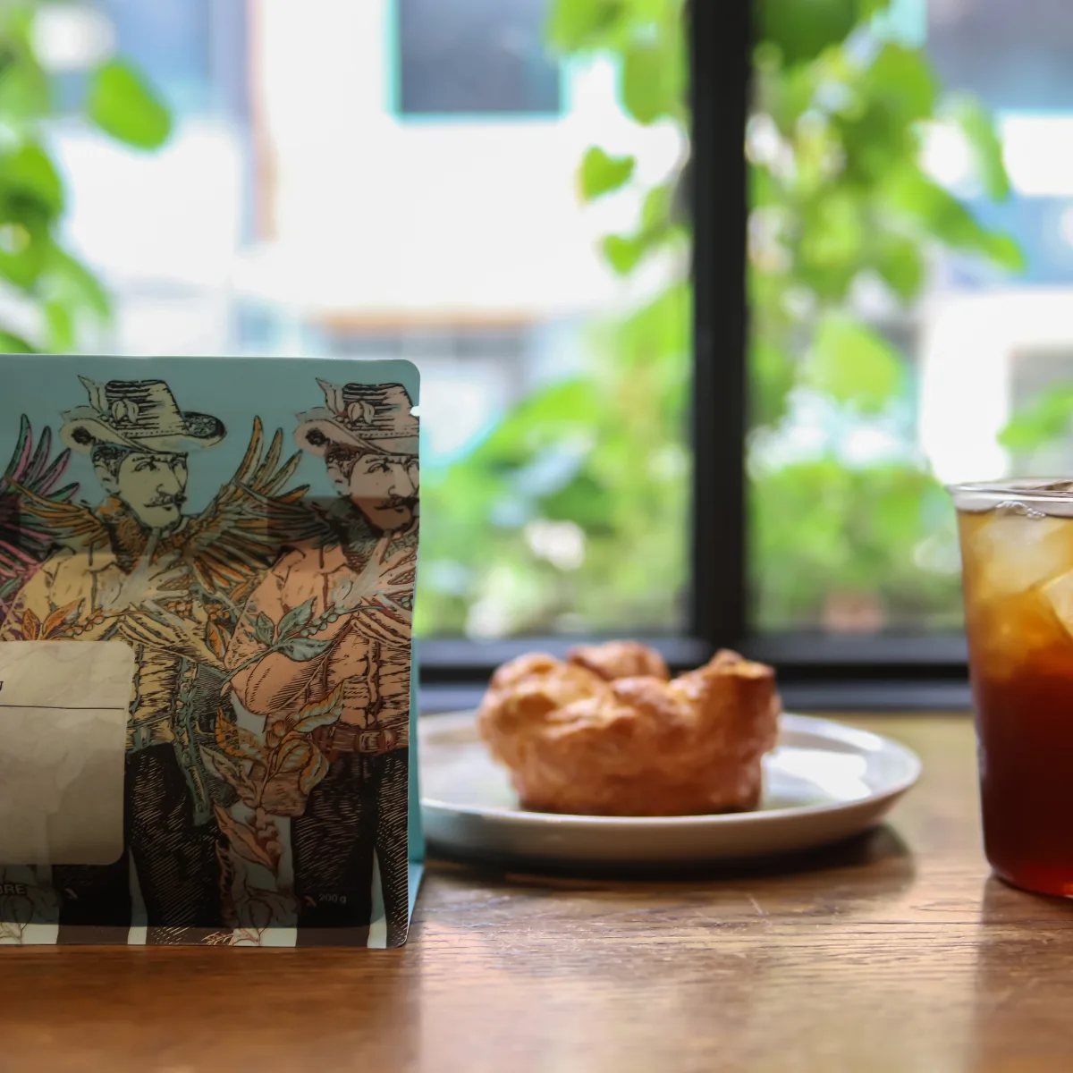 b.patisserie 孔徳店 — コーヒー豆袋と窓辺の観葉植物