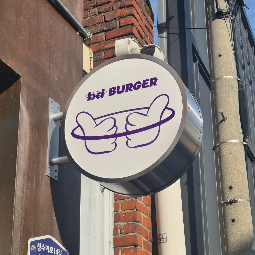 bdバーガー 聖水店 — レンガ壁に掲げたbd看板