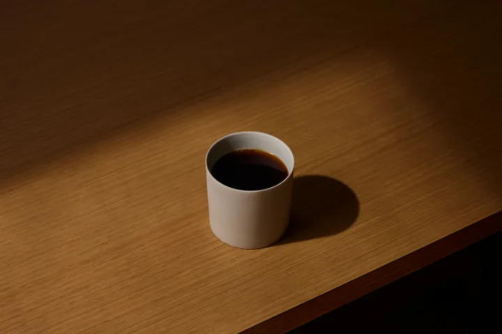 木の卓上に置かれた一杯のコーヒー