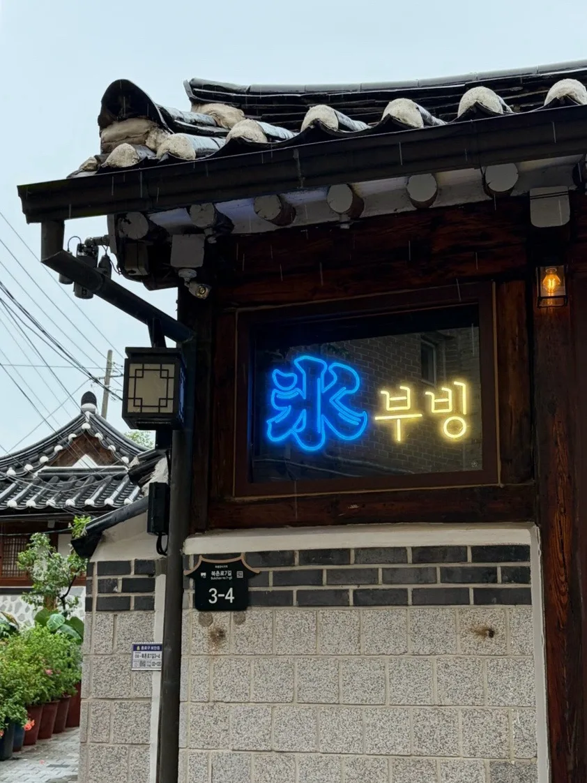 瓦屋根の韓屋と青い「氷」のネオン看板