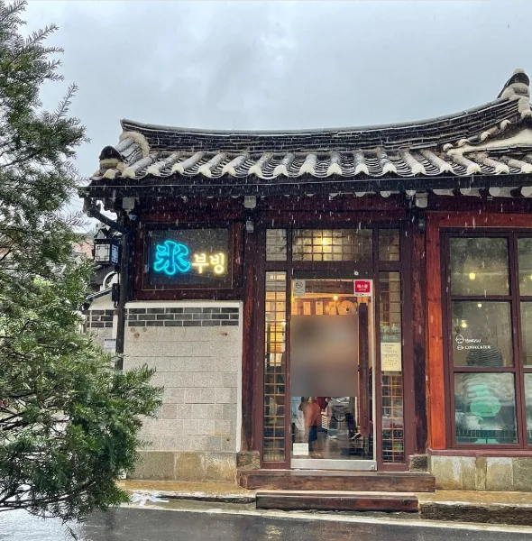 雪の中の韓屋店舗とネオン看板