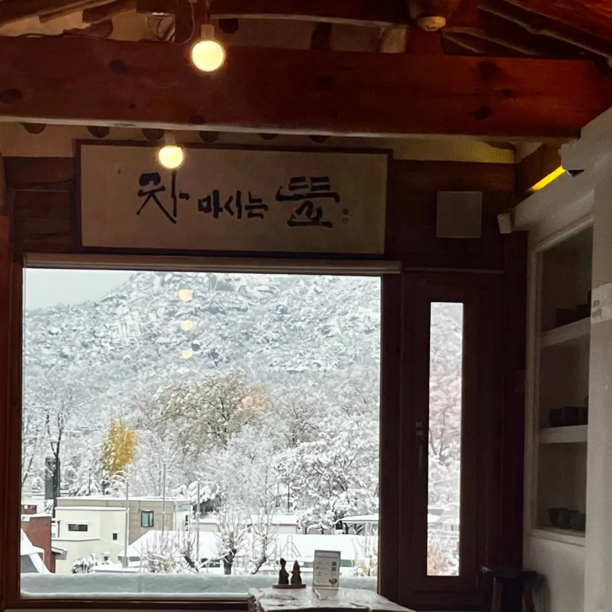 店名額と窓越しの雪山