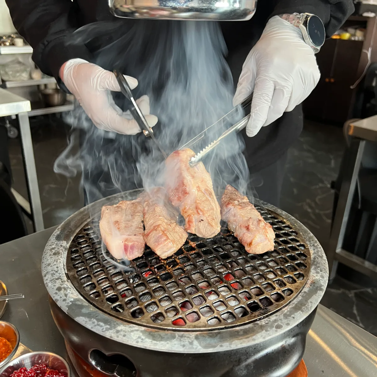 手袋をした店員が炭火で肉を焼く様子