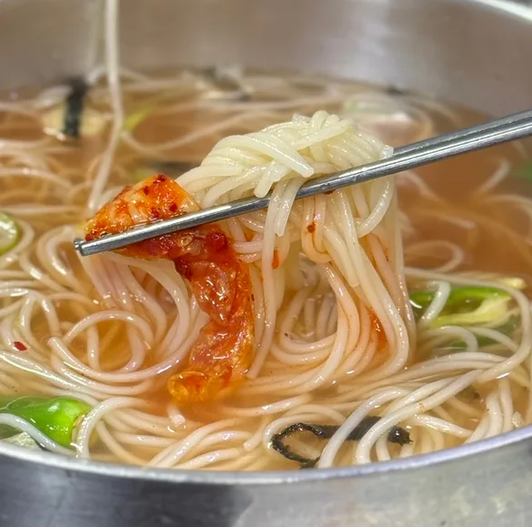 箸で持ち上げた汁麺とキムチ
