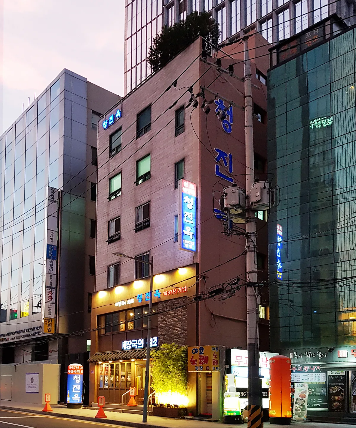 清進屋 — 夕暮れに灯る青い店名看板