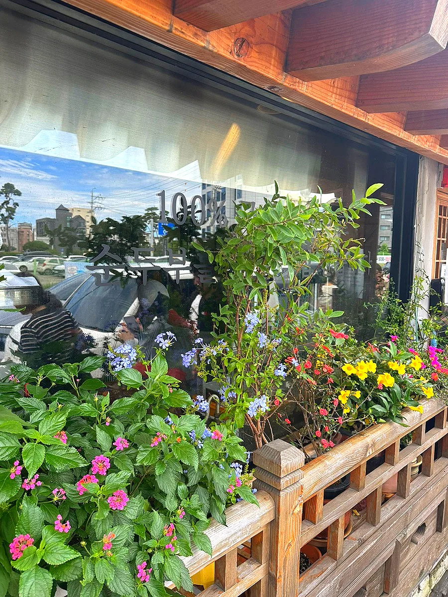 チェイルスン・スンドゥブ — 花に囲まれた店舗の窓辺