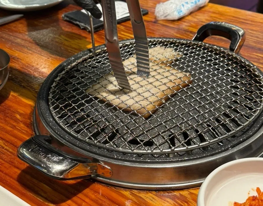 器具で押さえて焼かれる豚皮