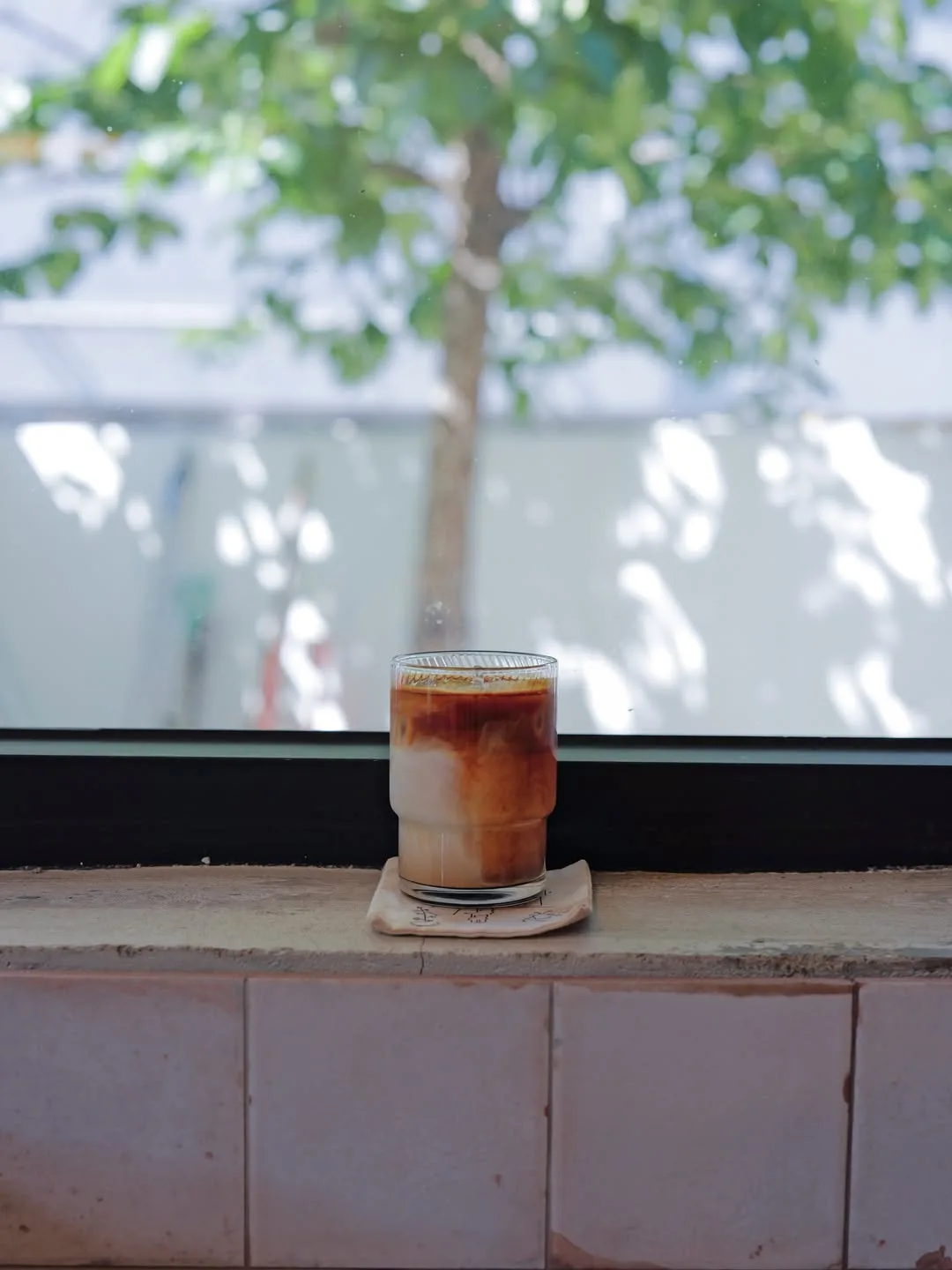 COSIA COFFEE 薬水店 — 窓辺に置かれたアイスラテ