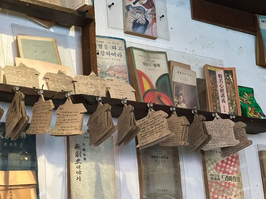 古書と紙札が並ぶ壁棚