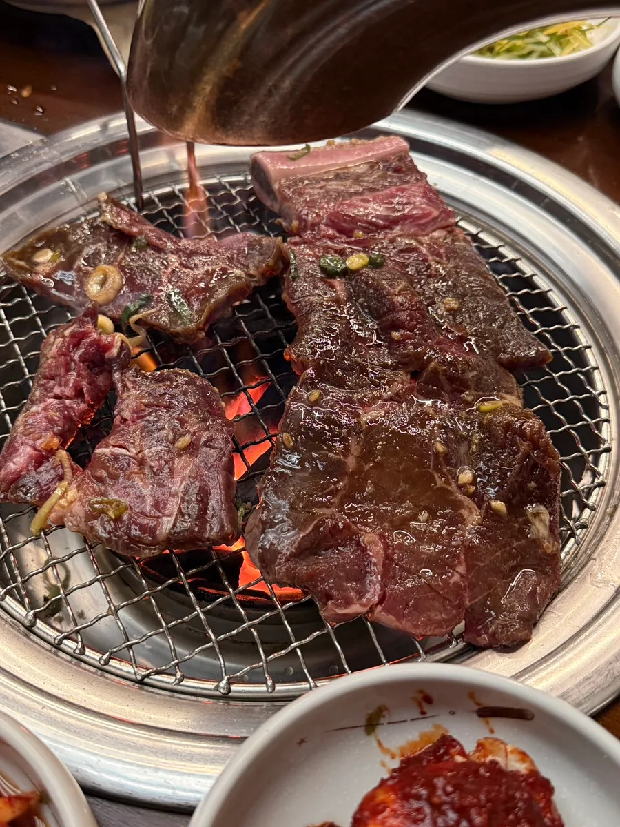炭火網で焼く骨付き牛肉