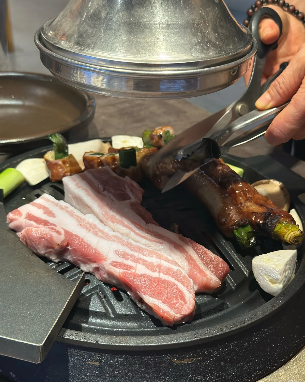 卓上の鉄板で肉を切り分ける様子