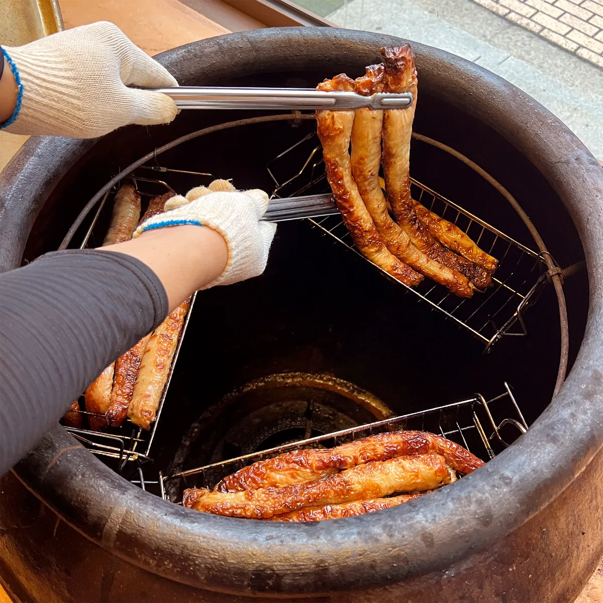 壺型の窯から下焼きしたマクチャンを取り出す様子