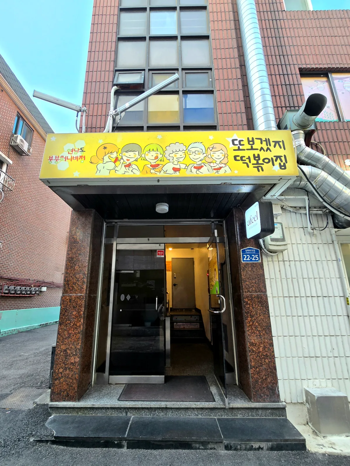 トボゲッチトッポッキ ブンブンハニービー店 — 黄色い看板を掲げた店の入口