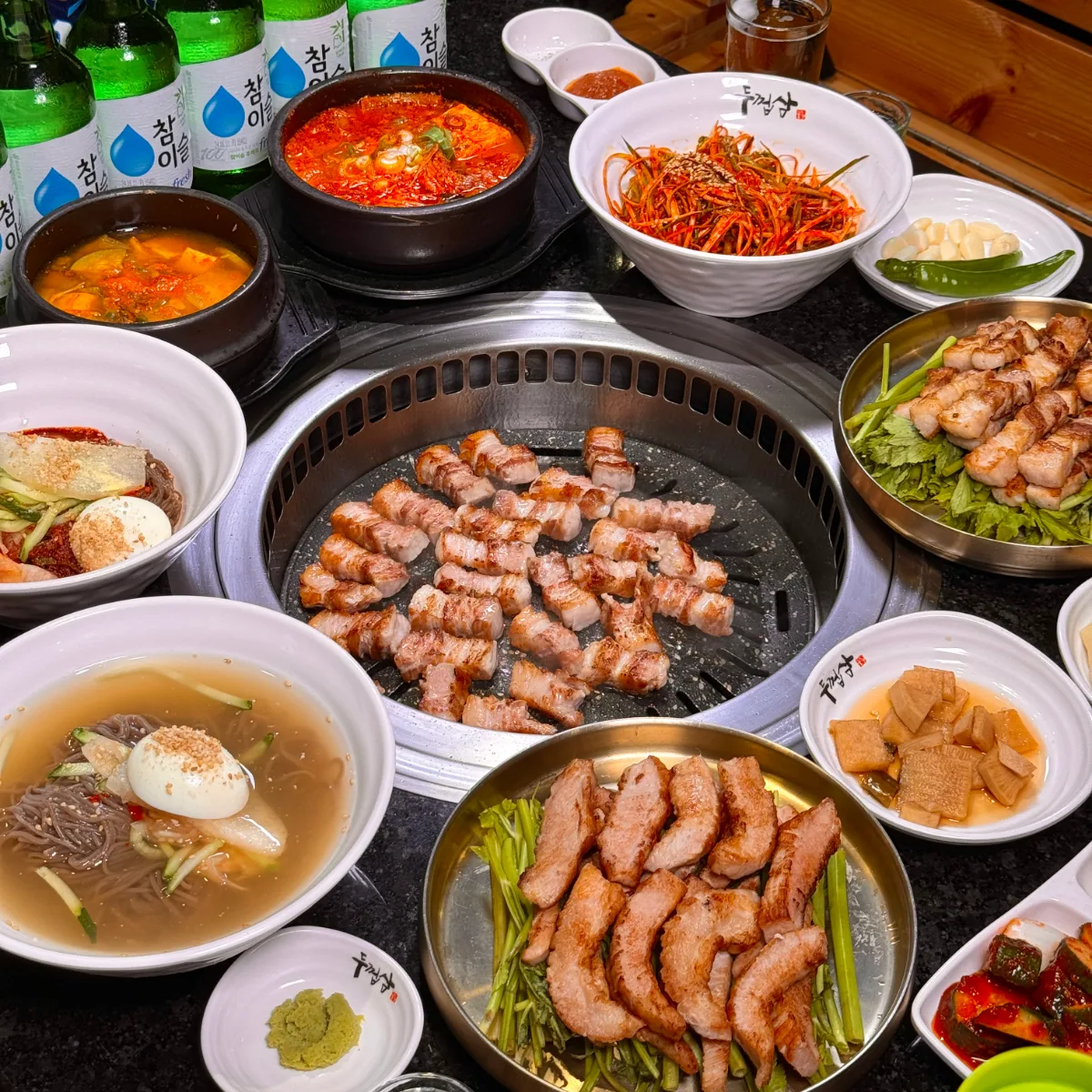 DOOKUPSAM 明洞直営店 — 焼肉と冷麺、チゲが並ぶ食卓