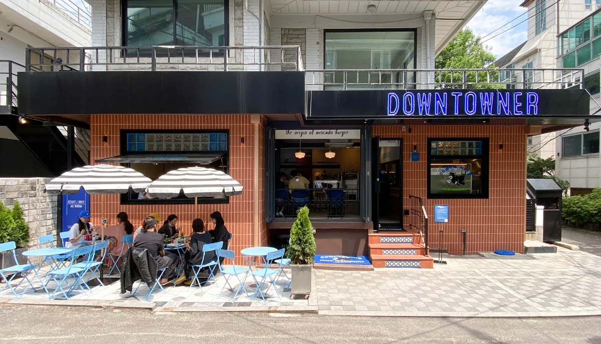 DOWNTOWNER 清潭店 — 青い看板とテラス席の店舗