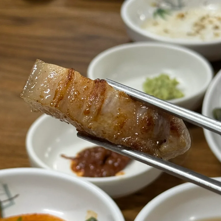 Duroomi 本店 — 箸で持ち上げた焼き上がりのオギョプサル
