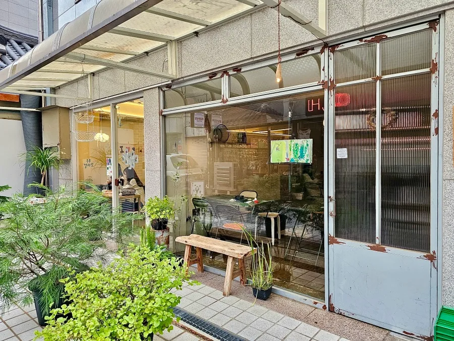 コチョ — 緑と木製ベンチのある店先