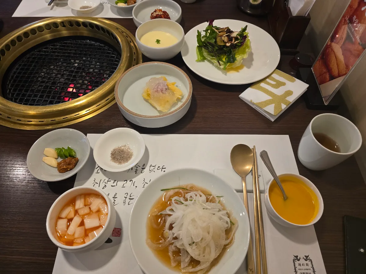 巨大カルビ — 冷麺と小皿料理が並ぶ食卓