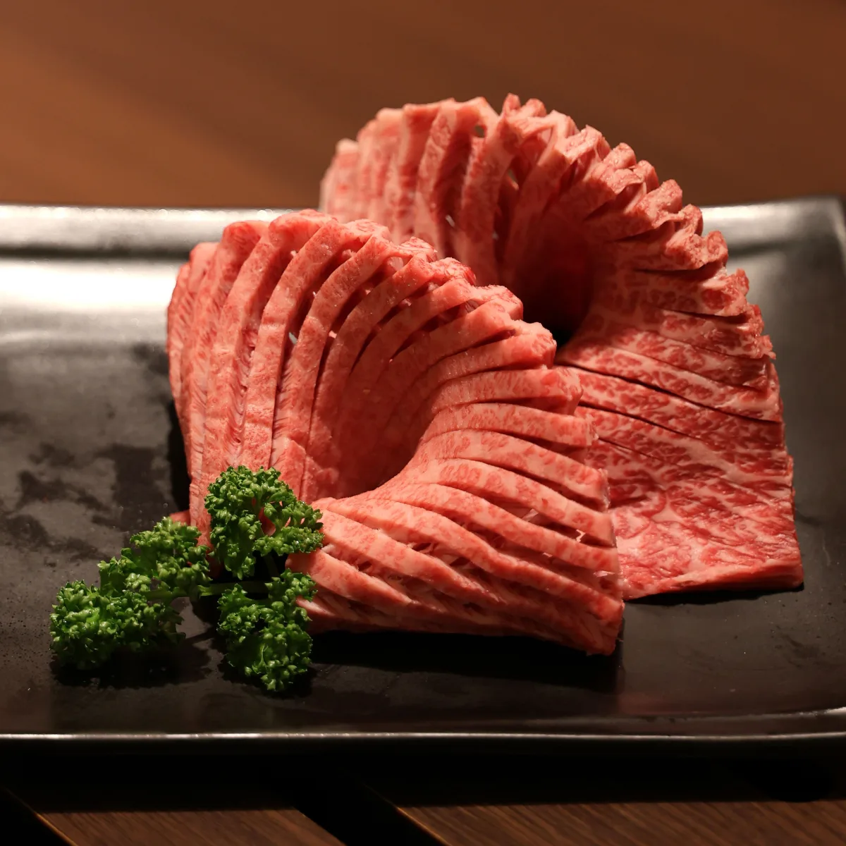 巨大カルビ — 黒い皿に盛られた霜降り肉