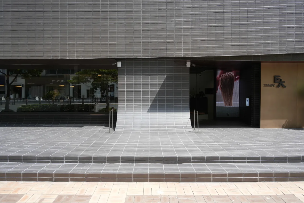 巨大コムタン 海雲台本店 — 灰色タイル壁と看板が並ぶ入口外観