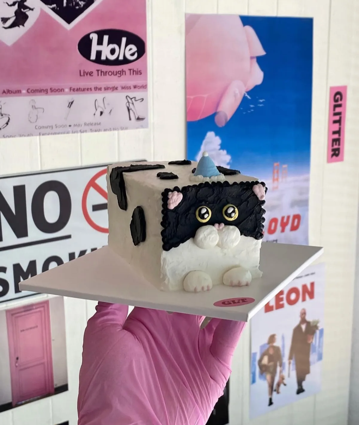 ポスターを背景にした白黒猫型ケーキ