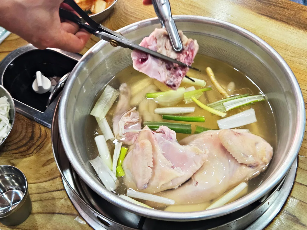 鍋の鶏をはさみで切り分ける