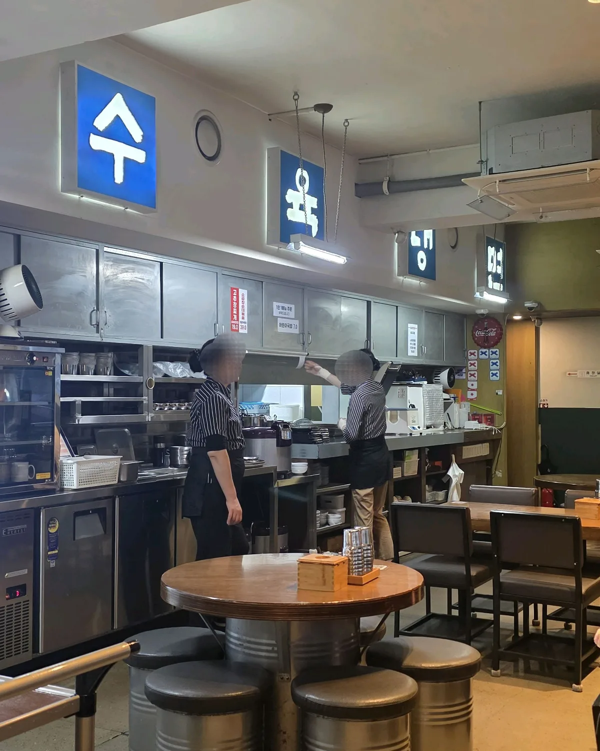 光化門クッパ 本店 — 青い料理札が並ぶ厨房