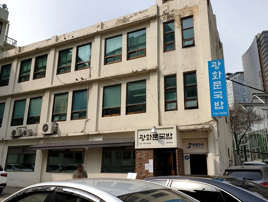 青い縦看板が掛かる白い建物