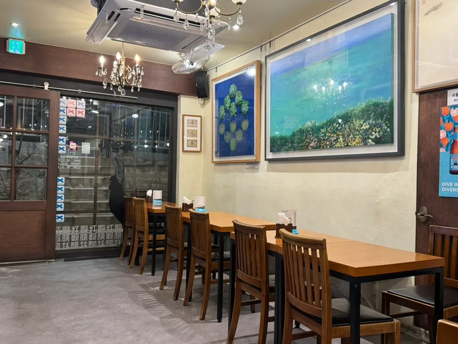 鷄熱社 本店 — 絵画と木製テーブルの客席