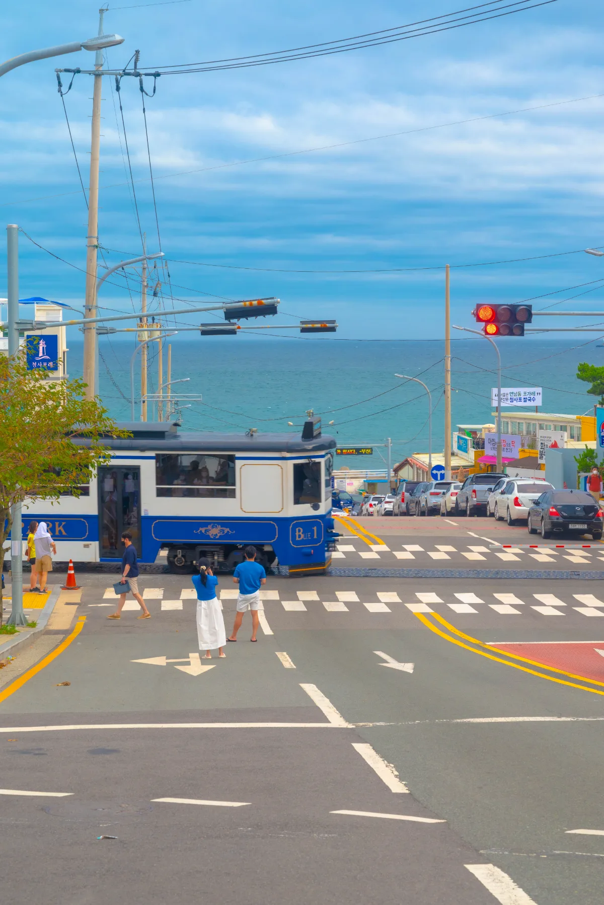 海辺の交差点を横切る青い列車