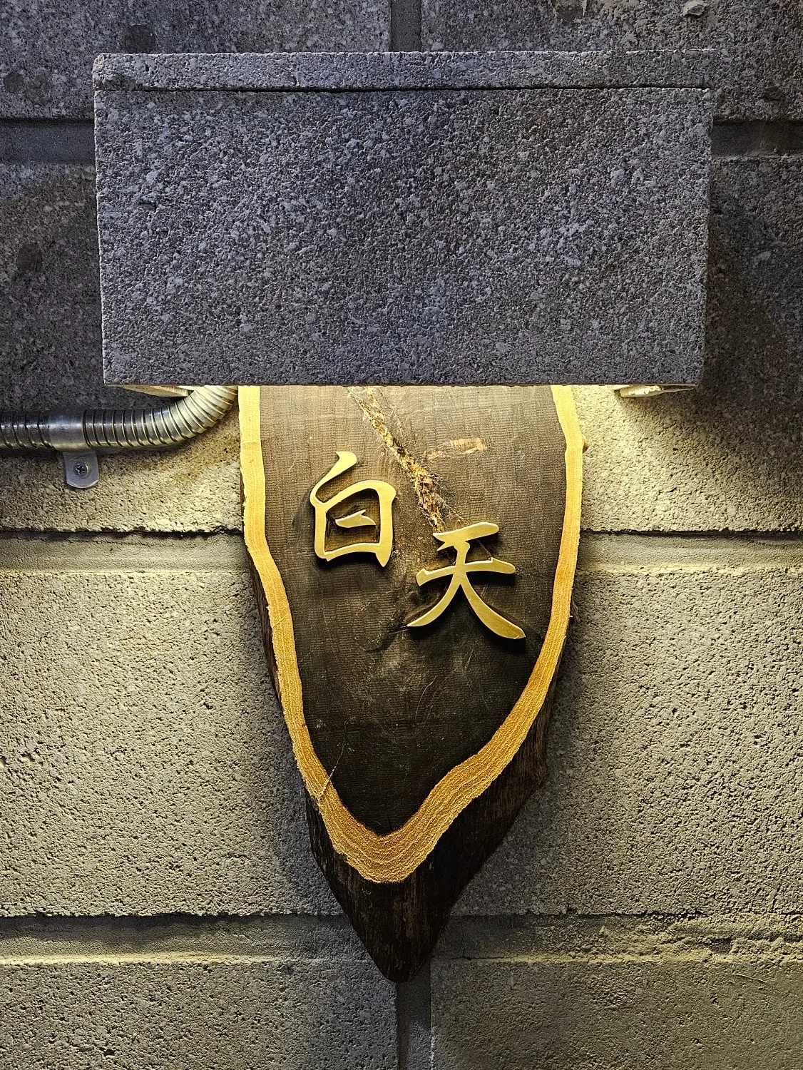 石壁に浮かぶ「白天」の木製看板