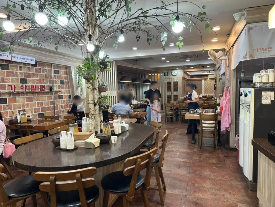 ハルメカヤミルミョン — 樹木を囲む丸テーブルの店内