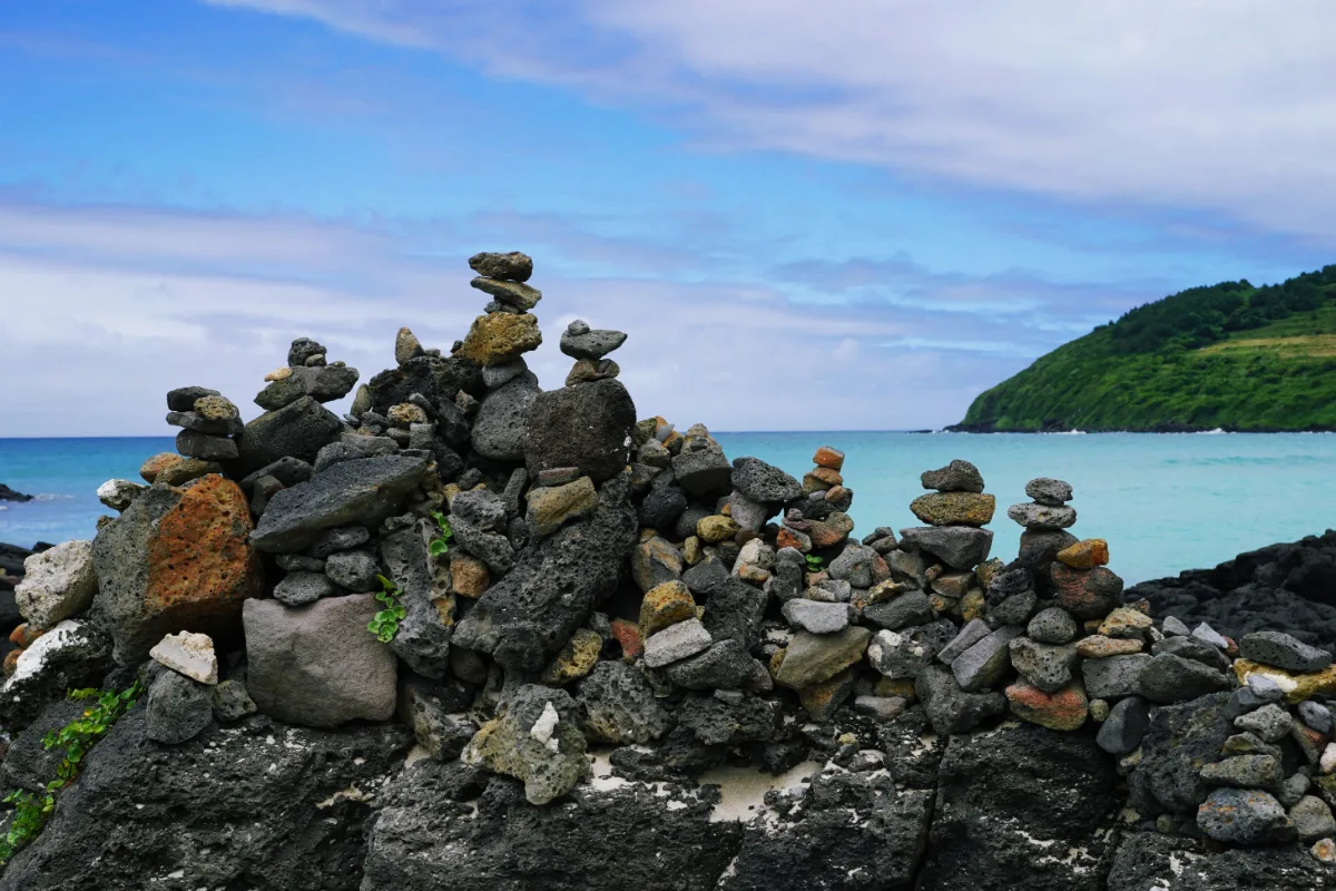 咸徳海水浴場 — 海辺に積まれた黒い石塔